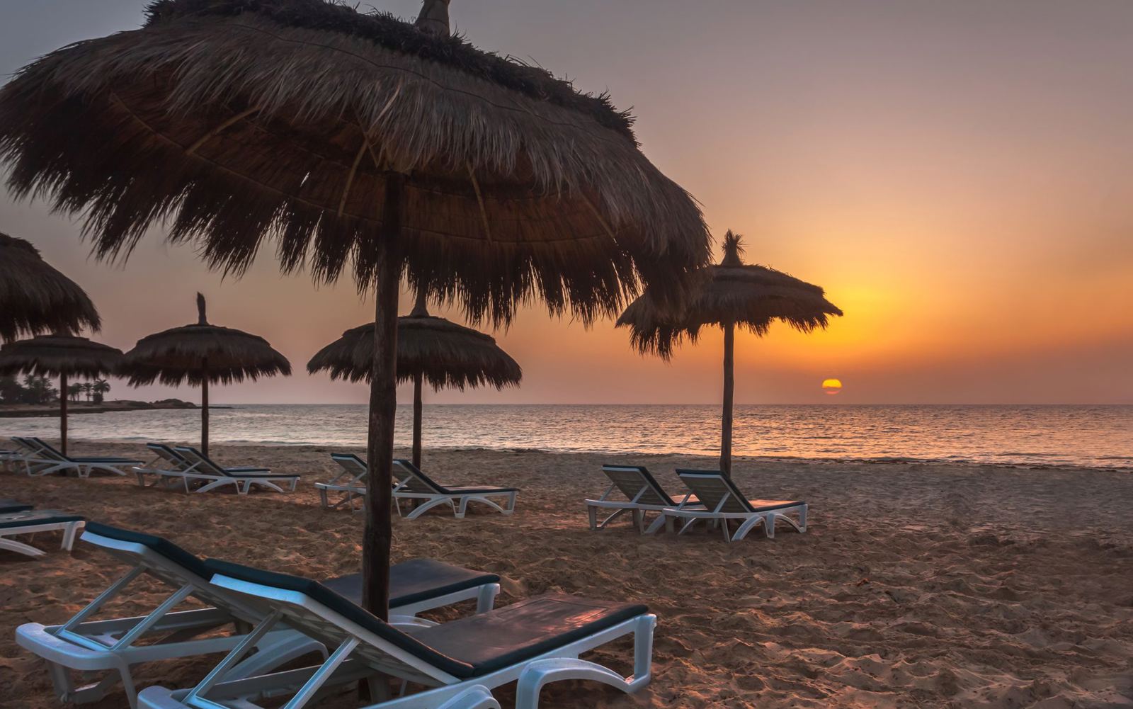 Sunset over the sandy beach with parasols at El Mouradi Djerba Menzel, Tunisia holiday - Just Sunshine Holidays